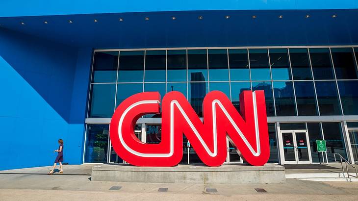 A blue building with a glass front and a red CNN logo in front of it