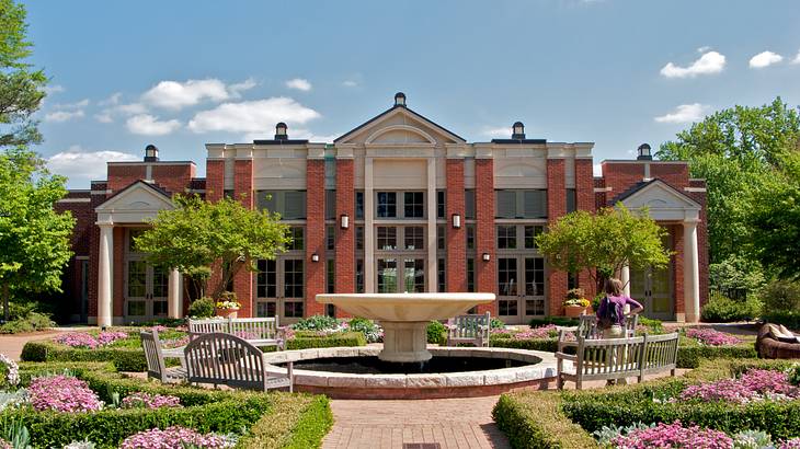 A white and red brick building with a garden in front of it