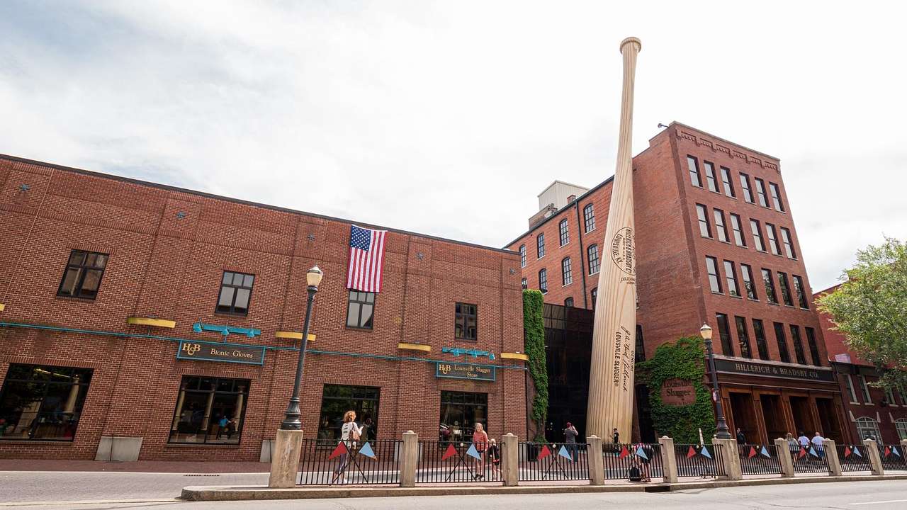A brick building with a large baseball bat statue in front of it