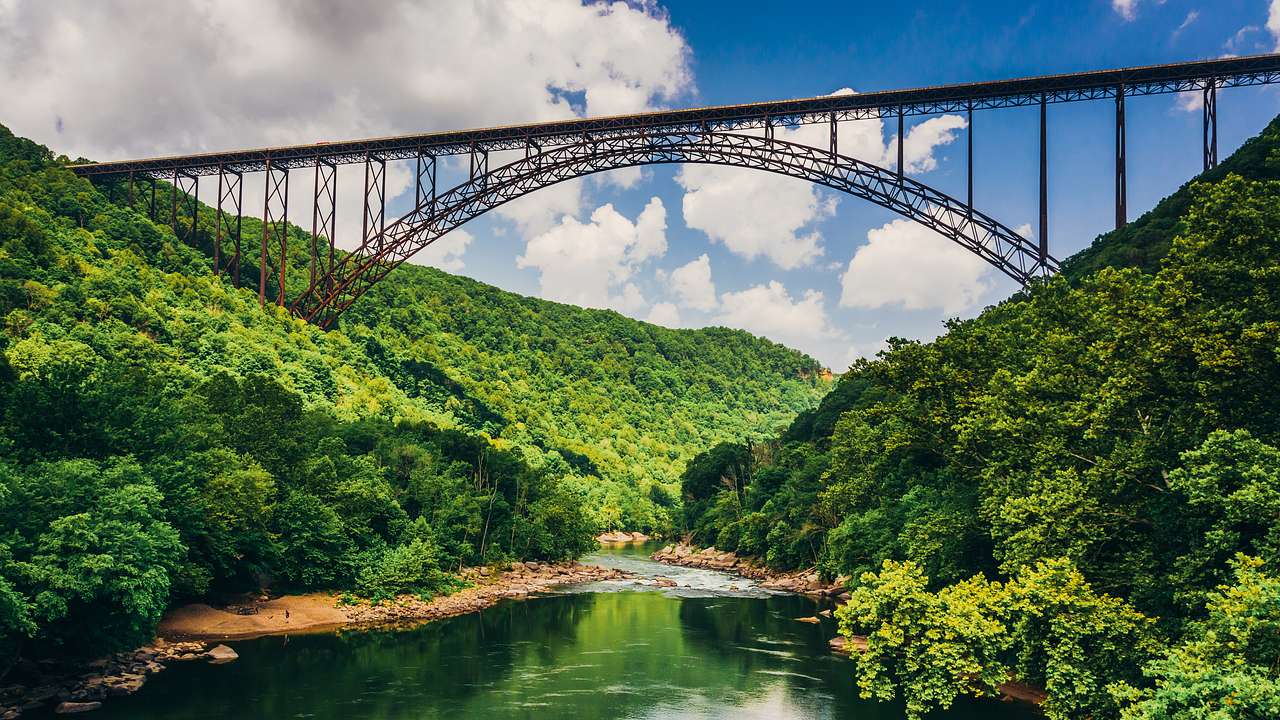 A steel bridge over a river in a lush valley