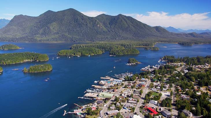An aerial of a harbour town surrounded by green islands and a green mountain behind