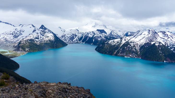 Panoramic view of snow-capped peaks with a blue lake in the foreground