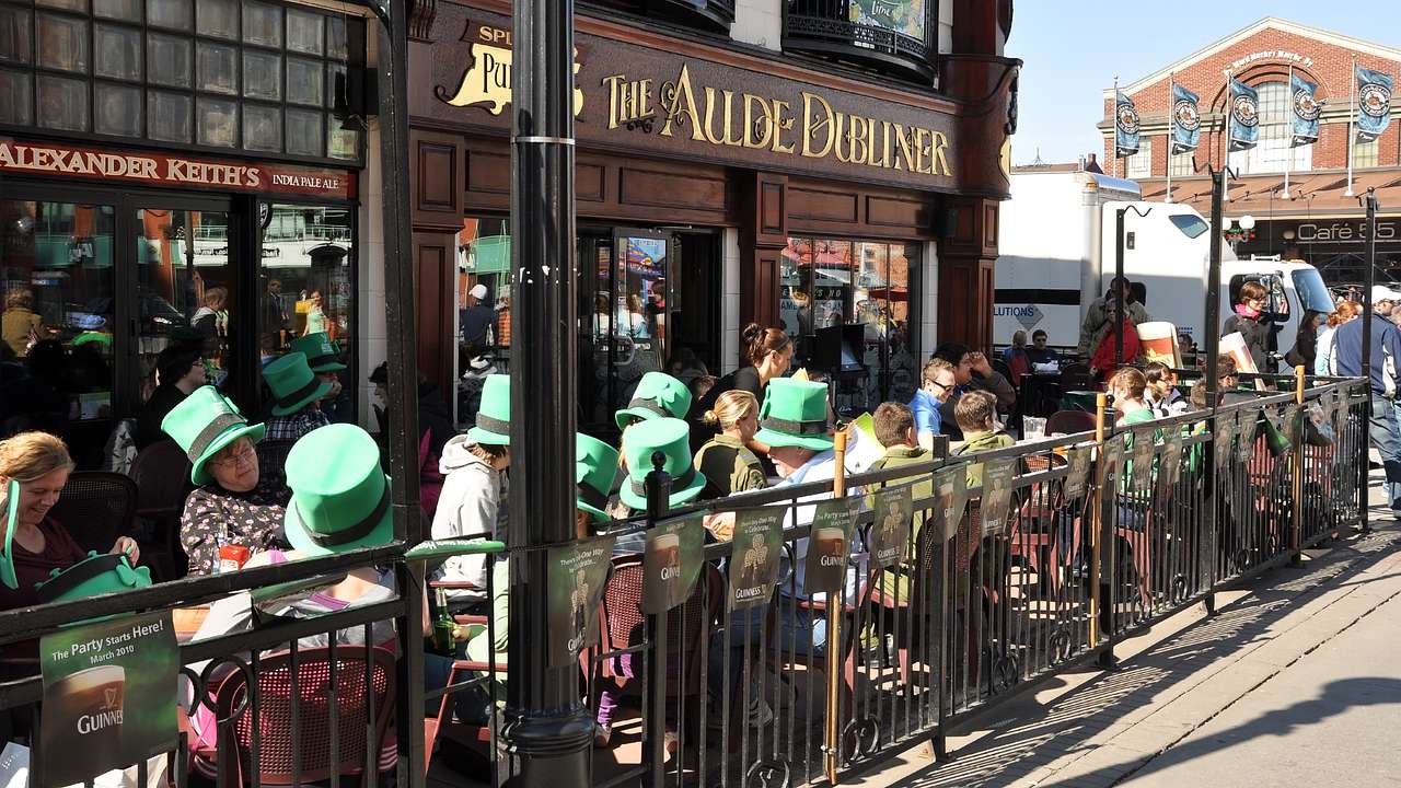 People sitting outside a pub on a sunny day drinking with tall green hats