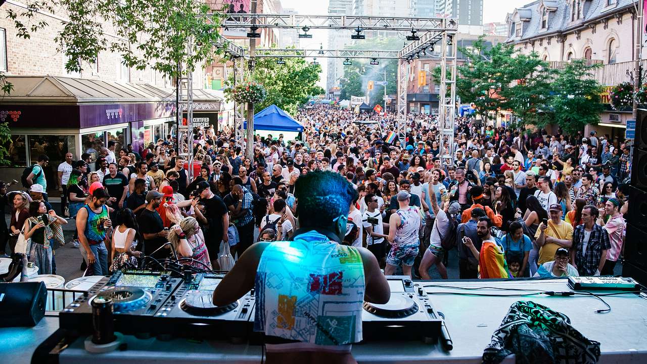 A DJ performing to a crowd of people wearing colorful outfits
