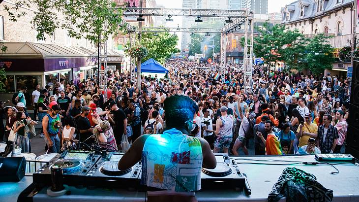 A DJ performing to a crowd of people wearing colorful outfits