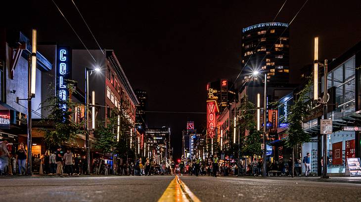 A low-angle view of people standing outside bars at nighttime