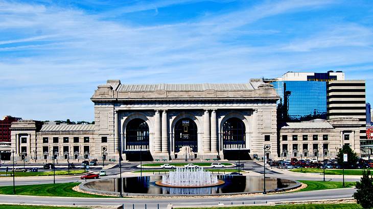 A large concrete building with a fountain in the foreground under a blue sky