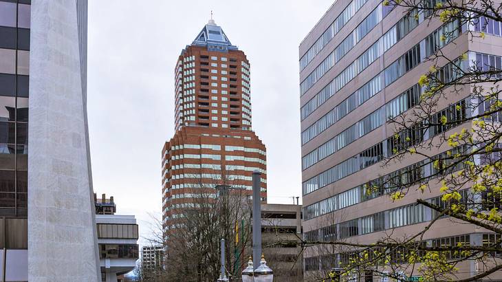 A tall orange-brick tower with many windows next to other buildings A tall orange-brick tower with many windows next to other buildings