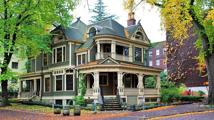 A Victorian-style house with a porch surrounded by trees A Victorian-style house with a porch surrounded by trees