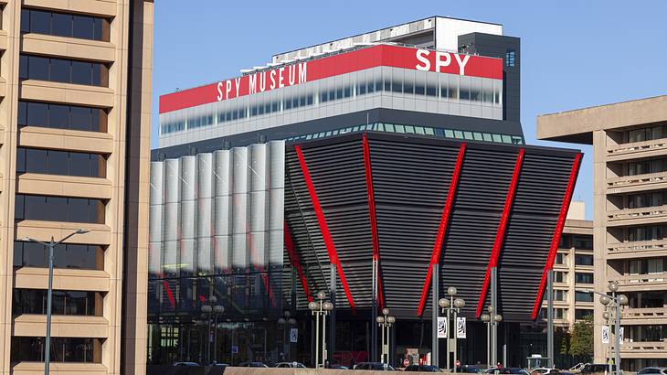 A building shaped like an inverted trapezoid with red accents and a "Spy Museum" sign