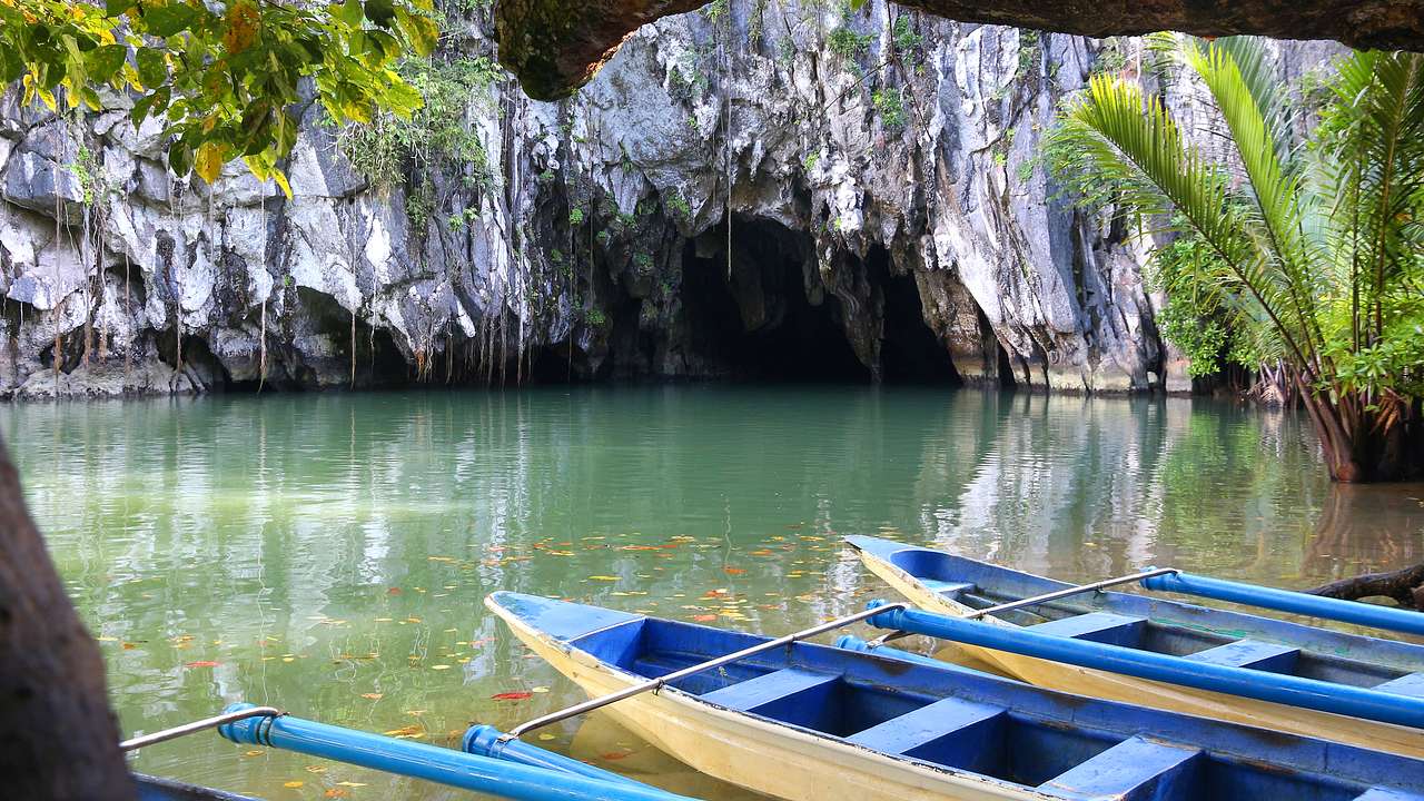 A cave with water flowing through it and boats on the water