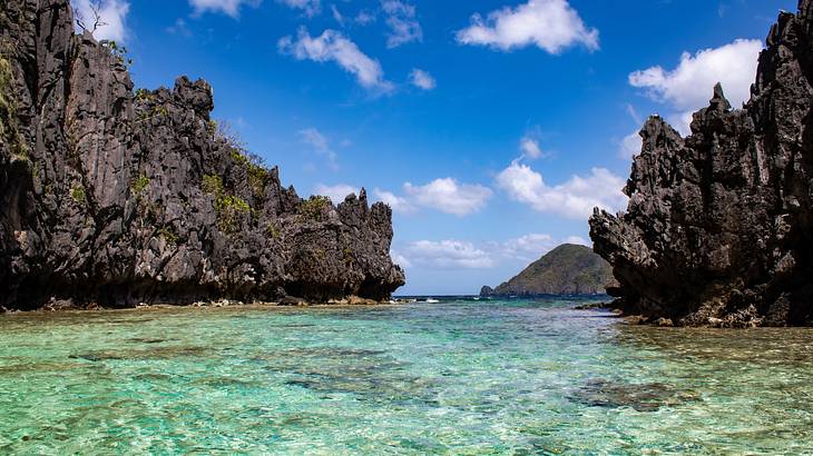 A blue lagoon surrounded by jagged rock cliffs under a blue sky