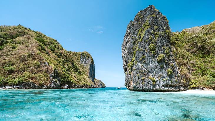 A rocky island surrounded by clear blue water and blue skies