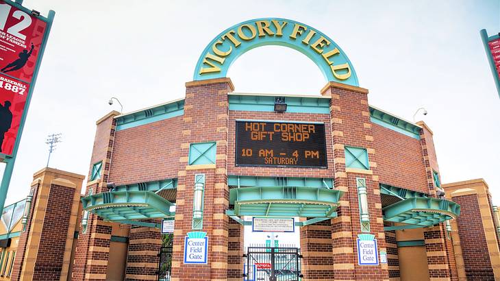 A gated brick entryway with an LED screen and a large "Victory Field" sign