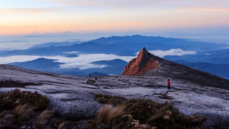 People watching a breathtaking sunrise at the top of Mount Kinabalu above clouds
