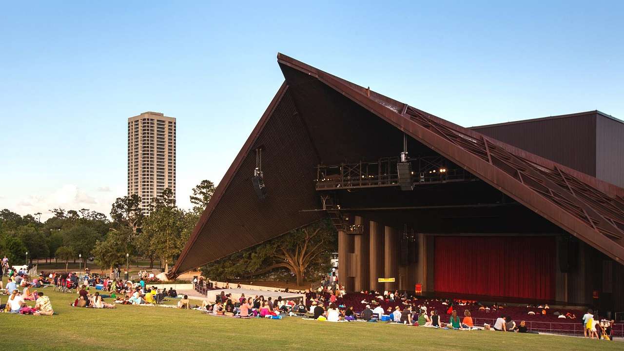 An open-air theater with a pointed roof and grass in front of it