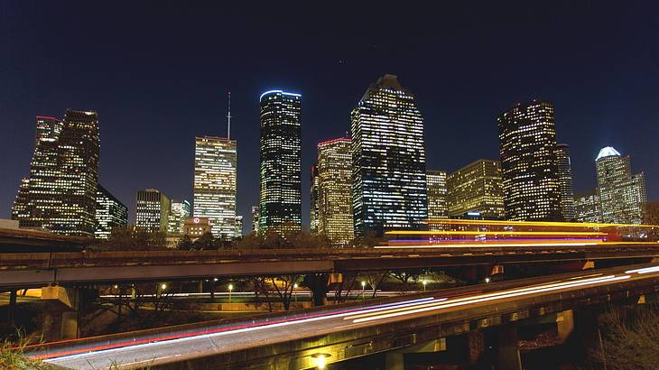 Buildings lit up at night with a highway in the foreground