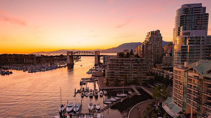 Aerial shot of Vancouver with buildings, a bridge, boats and water at twilight, BC