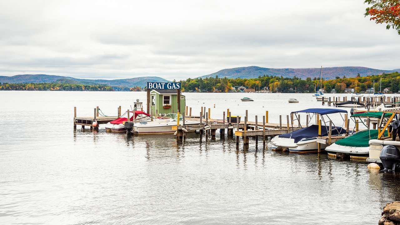 Small boats parked by a wooden pier with a fuel pump on a lake