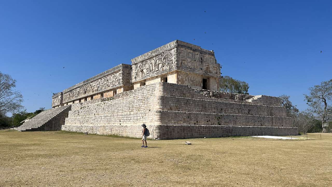 Large rectangular ancient ruins surrounded by grass and blue sky