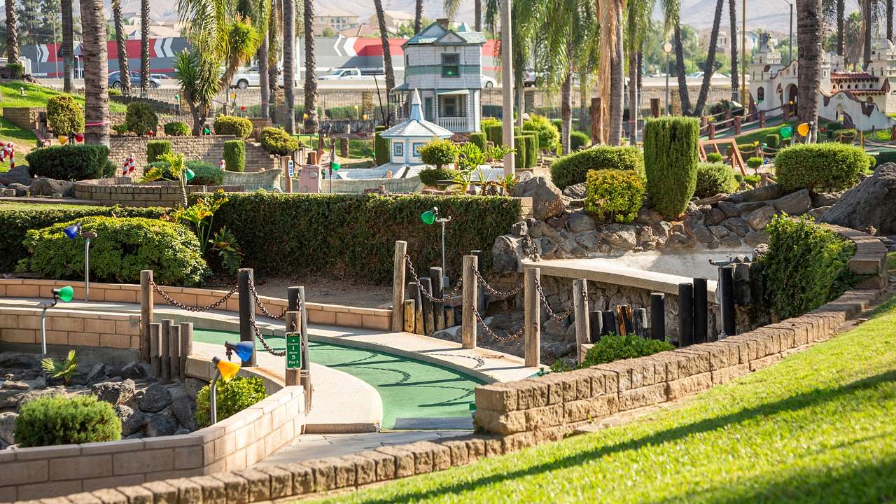 A section of a mini golf course next to grass and palm trees