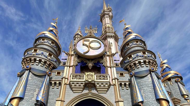 Entrance to a large gray castle with gold accents, with a round "50" sign above