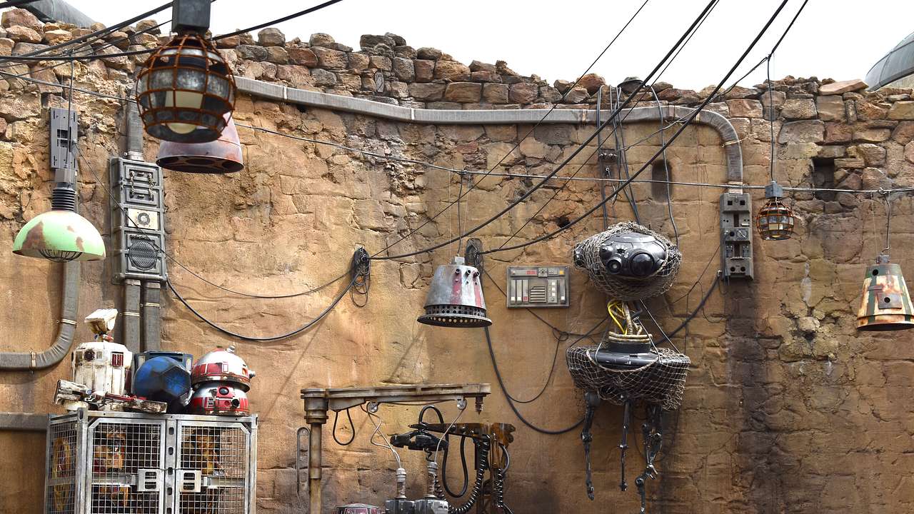 A stone wall with wires and metal gadgets attached to it and more wires overhead