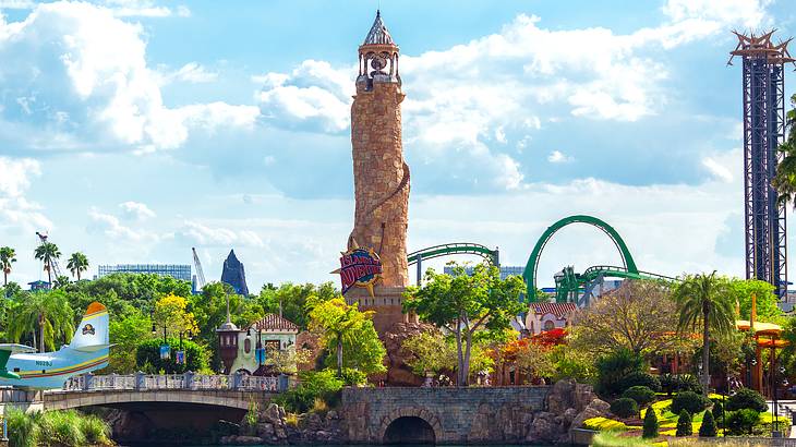 An orange lighthouse towering over a body of water, a bridge, and an amusement park