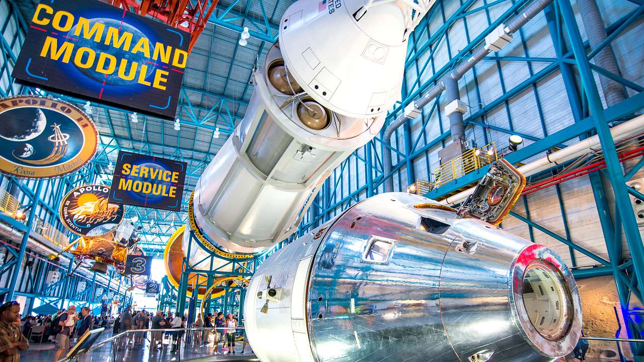 A huge white rocket ship in a museum lying horizontally, with signs overhead