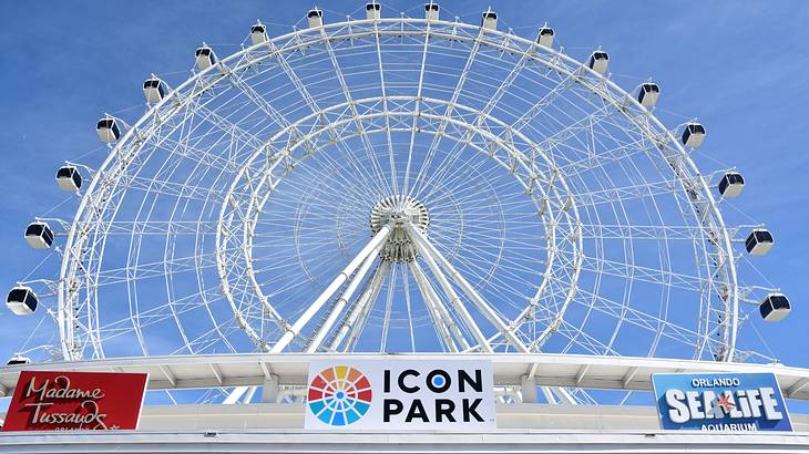 A huge, white Ferris wheel from below, with a sign underneath saying "Icon Park"