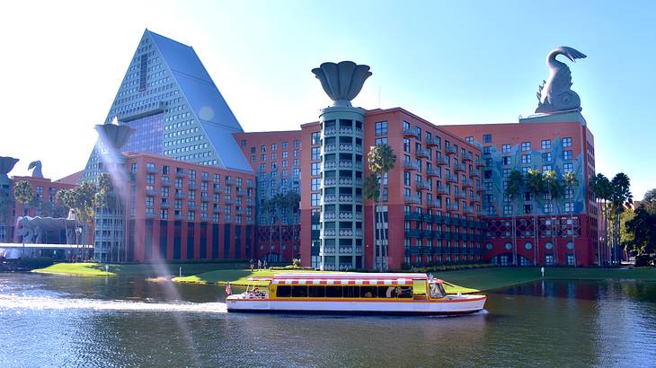 A huge red and blue building with many windows facing a body of water with a boat