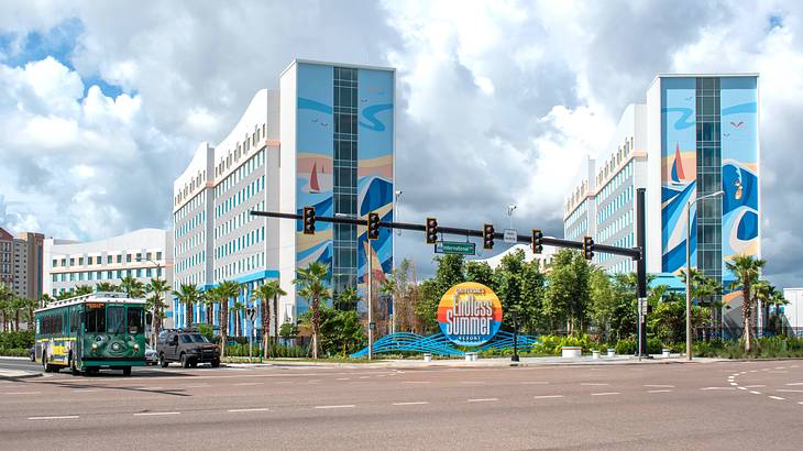 View across a street of two colorful large buildings facing a round sign and greenery