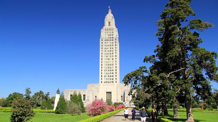 A tall tower building surrounded by a park with grass and trees under a blue sky