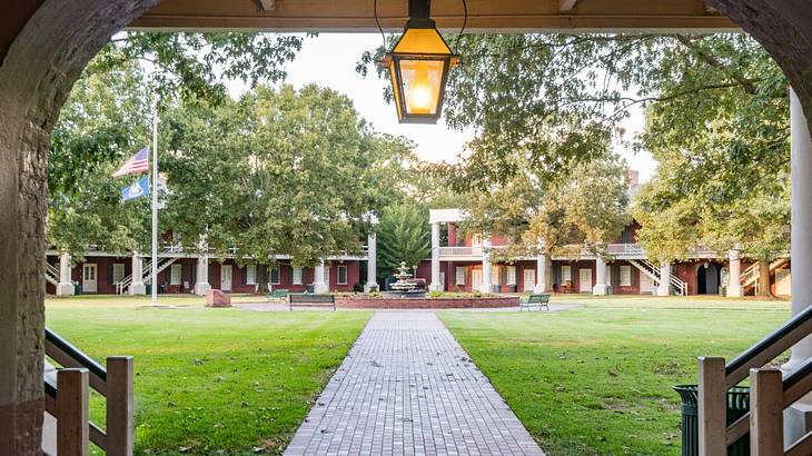 A path through the grass leading to a building with a fountain and flags outside it