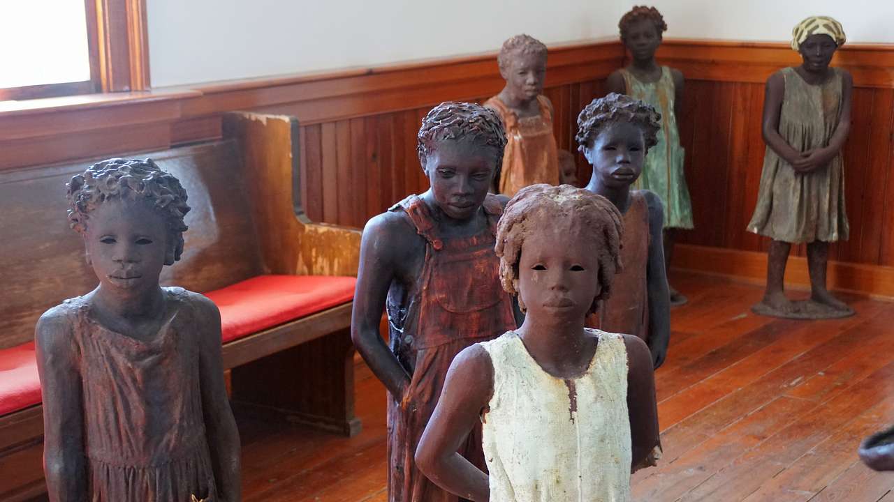 Statues of African children standing on a wooden floor