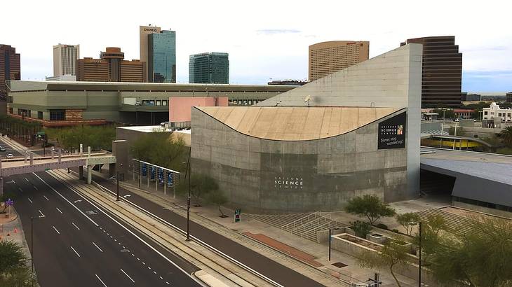 A triangular concrete building against a skyline, with a road in front