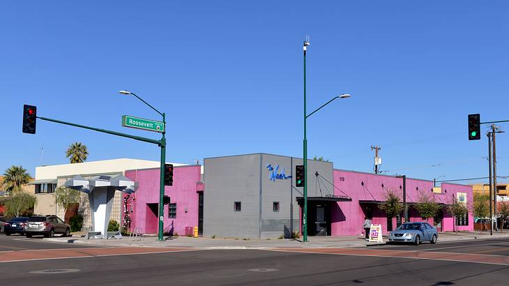 A magenta and grey building with a blue sign of "Nash" on the corner of a street