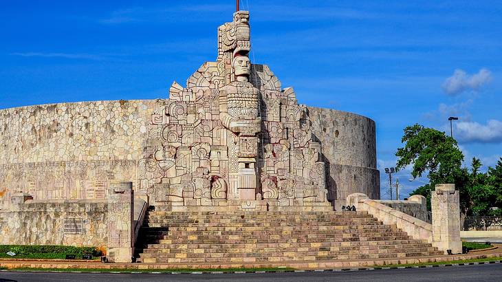 A stone monument with steps and a carved design on a clear blue day