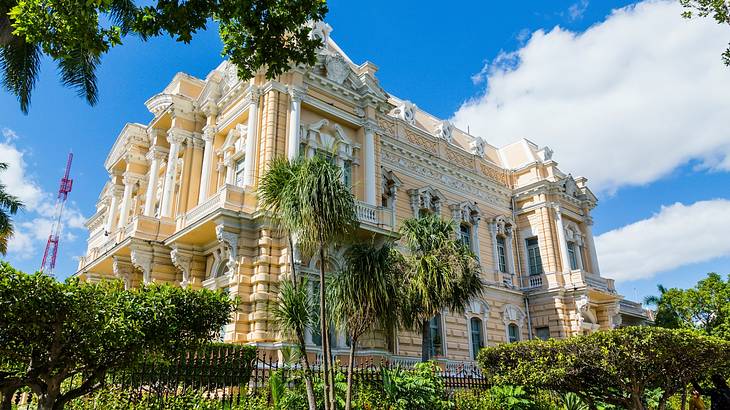 A large yellow and white mansion-style building surrounded by green trees