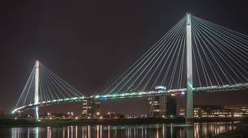A suspension bridge over the water illuminated at night