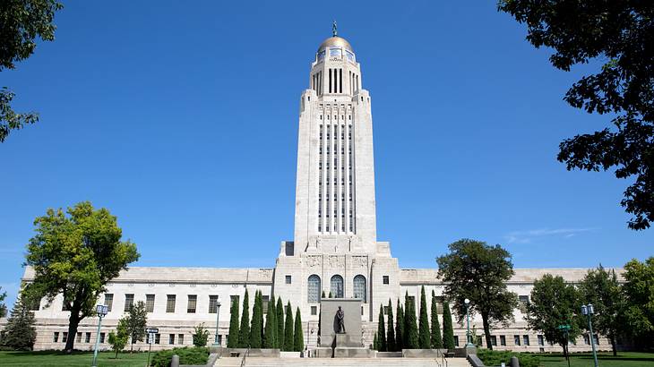 A large white building with a statue at the entrance surrounded by trees A large white building with a statue at the entrance surrounded by trees
