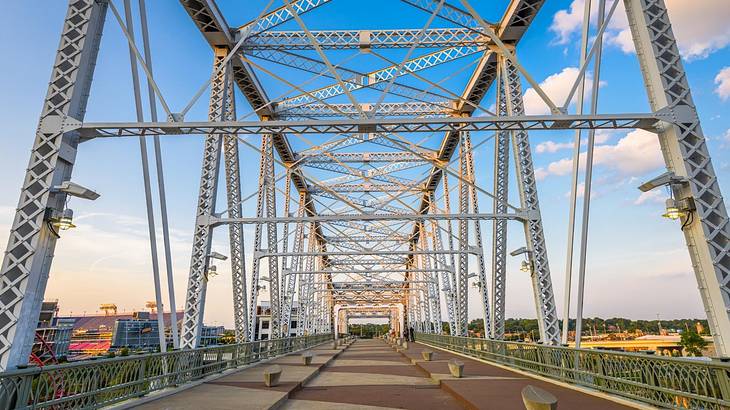 An iron bridge with pedestrian path under a blue sky with clouds