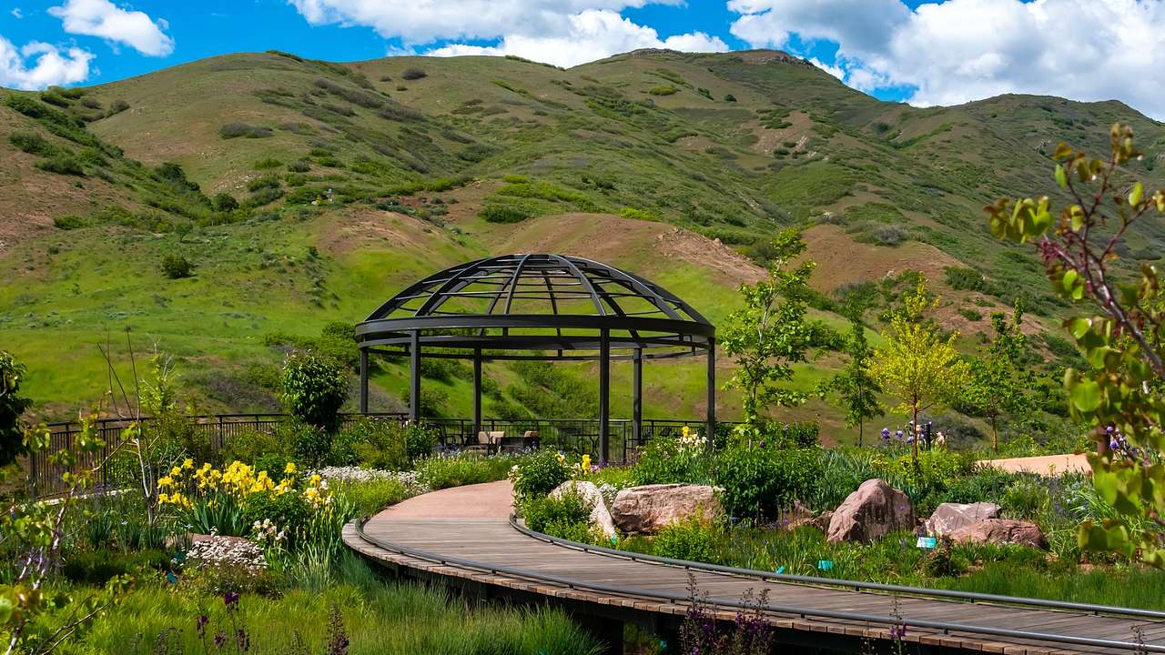 Grass-covered hills next to an iron structure, a wood path, and a garden