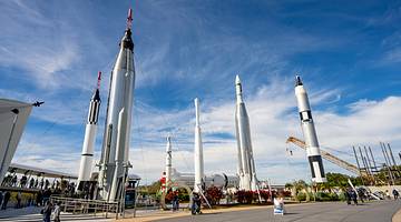 People wandering around a site with six space shuttles on a sunny day