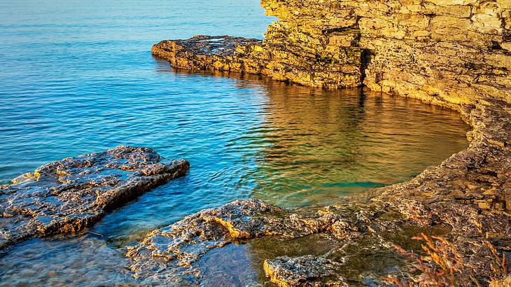 A natural water pool forms between rocky cliffs on a nice day