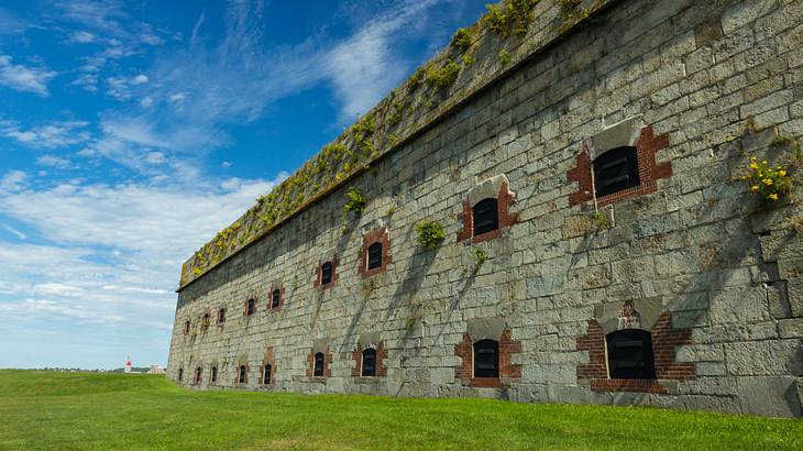 A large gray brick building with many small square windows on a grassy field A large gray brick building with many small square windows on a grassy field