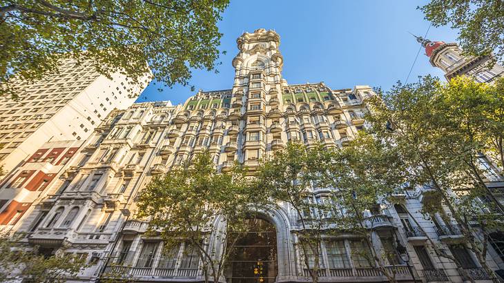 A majestic building with 22 floors and trees in the foreground under a clear blue sky