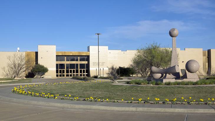 A museum building with a contemporary art sculpture and grass in front of it