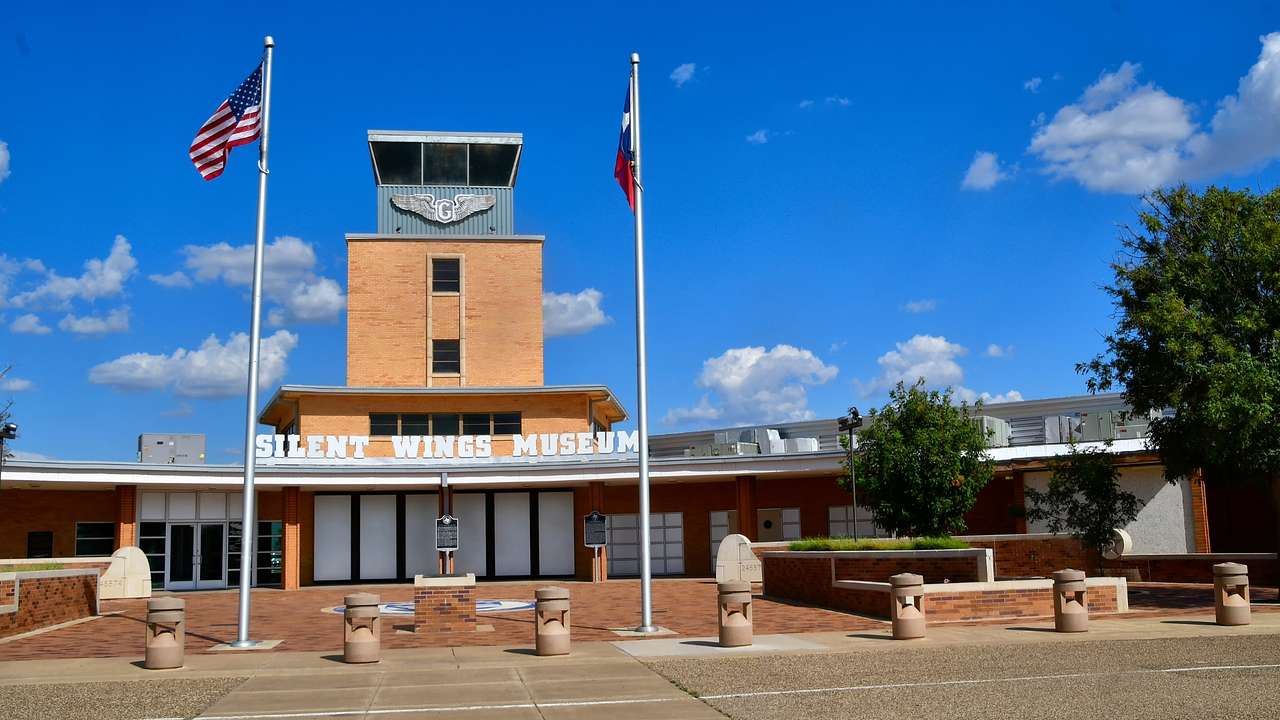A building with a "Silent Wings Museum" sign next to two US flags and a pathway