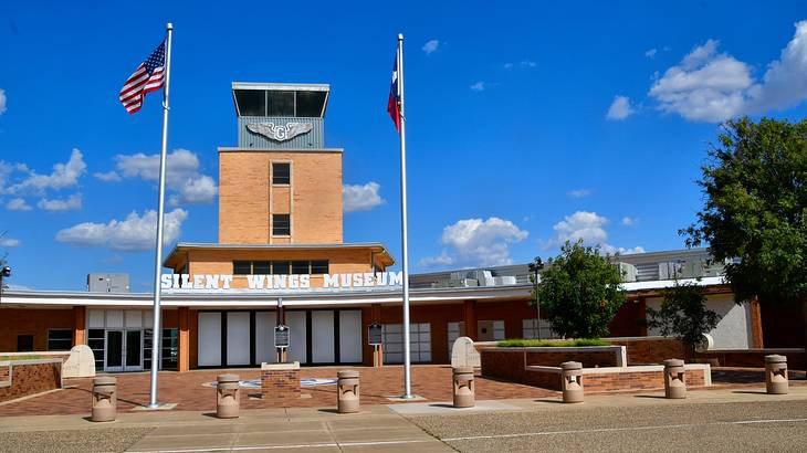 A building with a "Silent Wings Museum" sign next to two US flags and a pathway